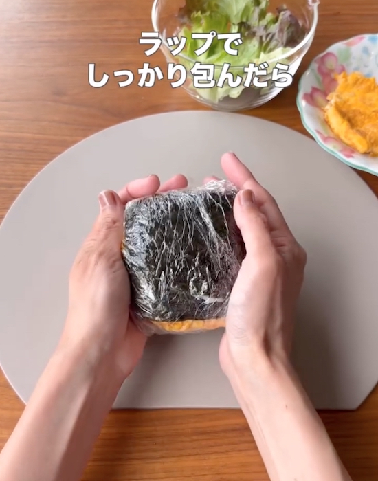 海苔で巻いた具材とごはんをラップに包む様子