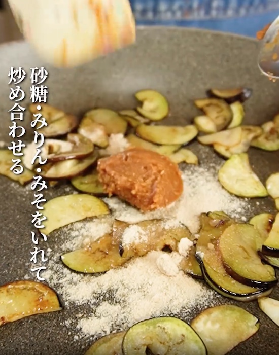 ナスの入ったフライパンに調味料を入れる様子
