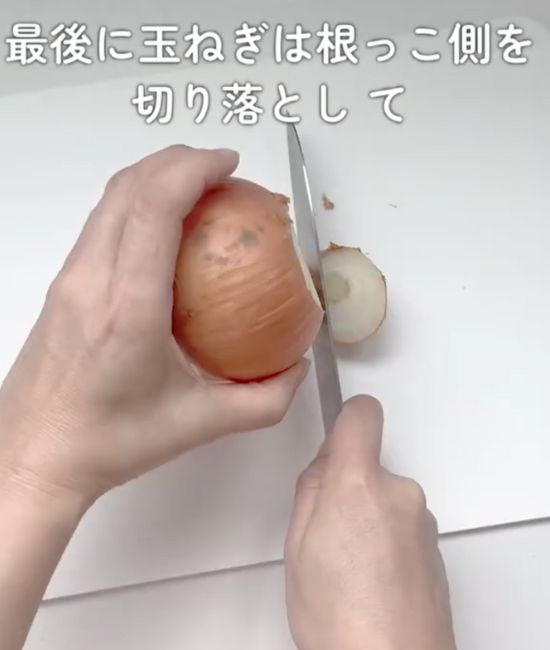 タマネギの根っこ側を包丁で切り落とす様子
