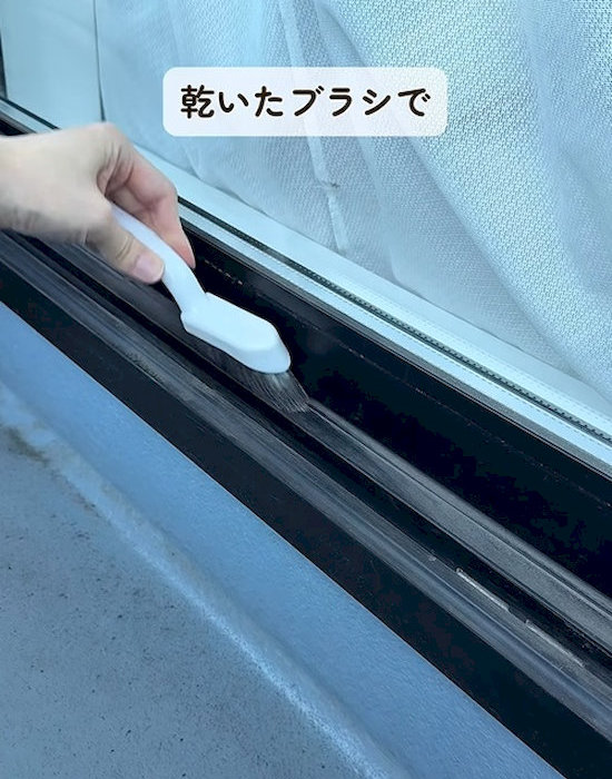 サッシをブラシで掃除する様子