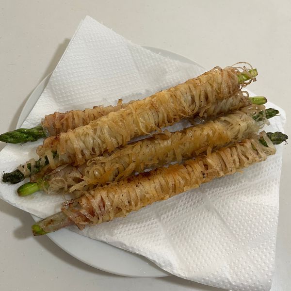 揚がったアスパラガスをキッチンペーパーを敷いた皿にのせた様子