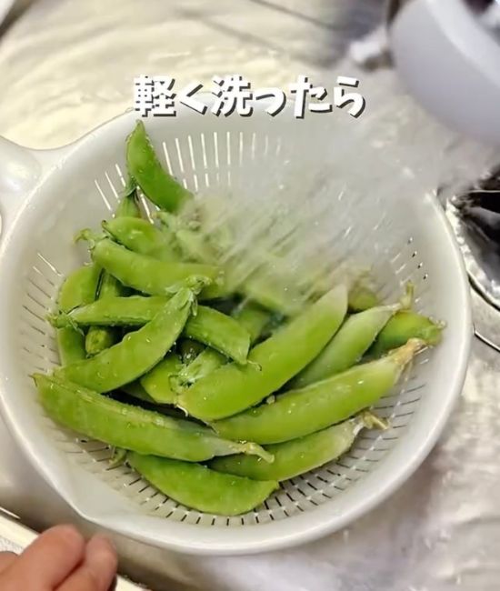 スナップエンドウをザルに入れて流水で洗う様子