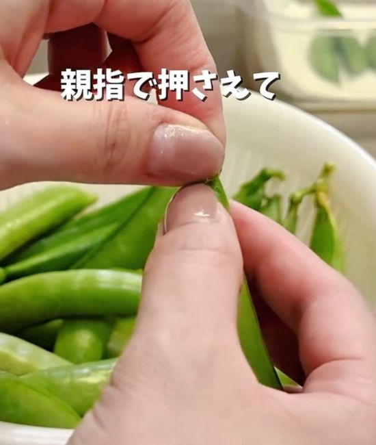 スナップエンドウのヘタの部分をつまむ様子