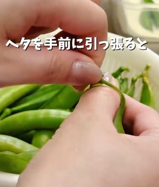 スナップエンドウのヘタを手前に引っ張る様子