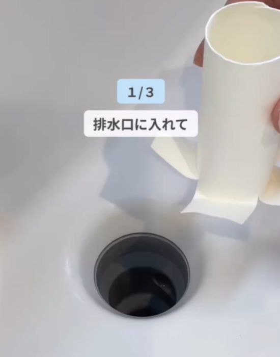 カットしたトイレットペーパーの芯を排水口に入れている様子
