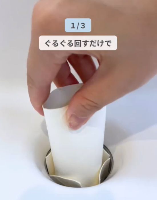 カットしたトイレットペーパーの芯を排水口でぐるぐる回している様子