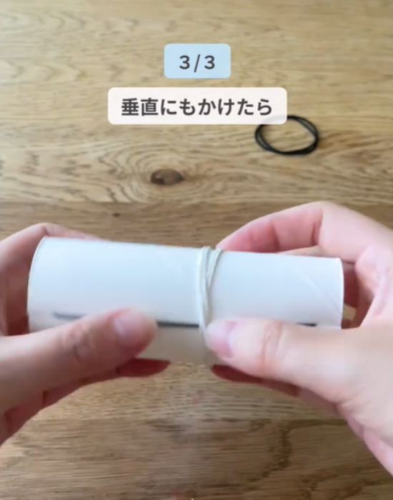 カットしたトイレットペーパーの芯に垂直になるように輪ゴムをかけている様子