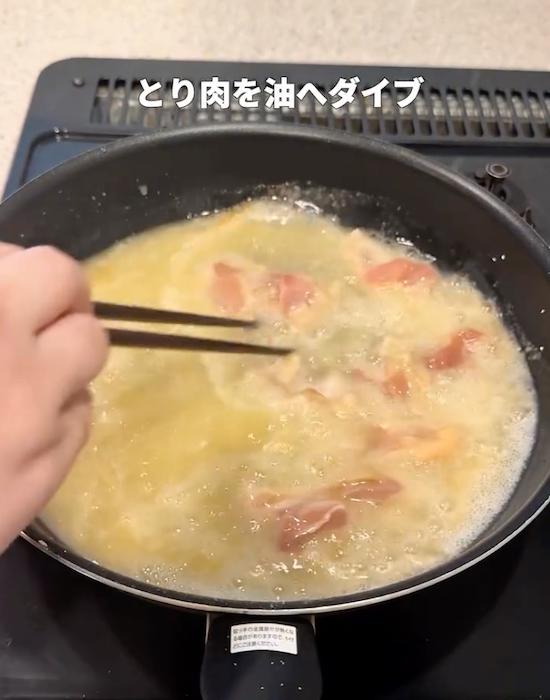 鶏肉を油の入ったフライパンに入れる様子