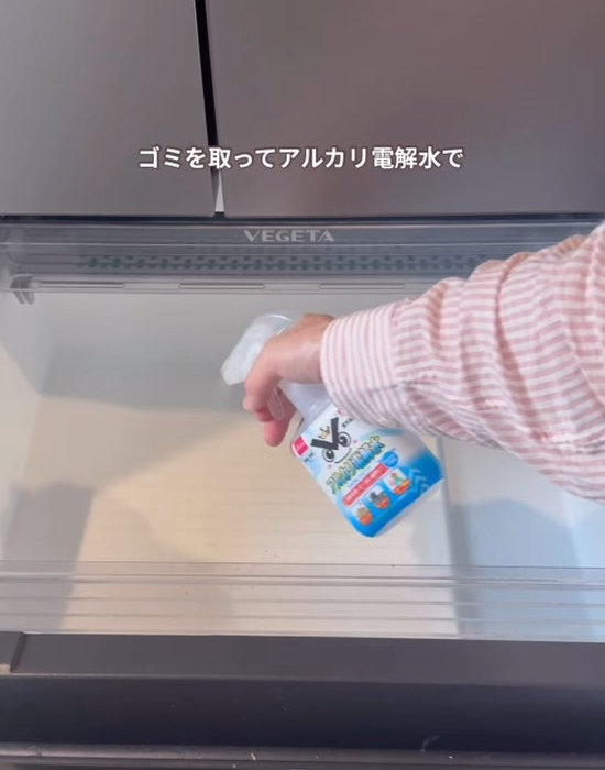 空の野菜室にアルカリ電解水スプレーを吹き付ける様子