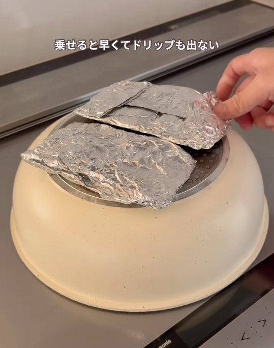 フライパンの裏側に肉の入ったアルミホイルを置く様子