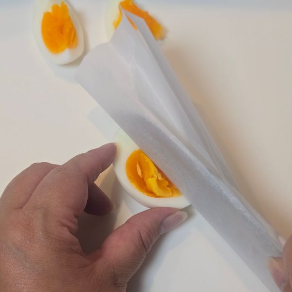包丁にクッキングシートを巻いてゆで卵を切る様子