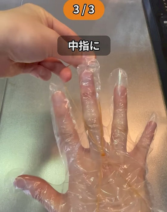 連結した輪ゴムを手袋を付けた手の指にかけている様子
