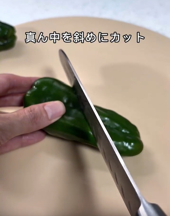 ピーマンを真ん中で斜めにカットする様子