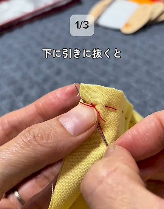 針を糸の下に向かって引いている様子