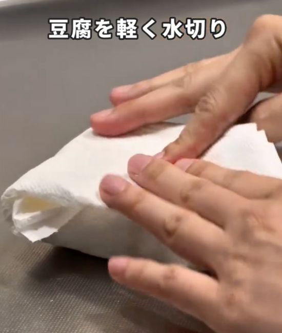 キッチンペーパーで豆腐を包んで軽く押さえる様子