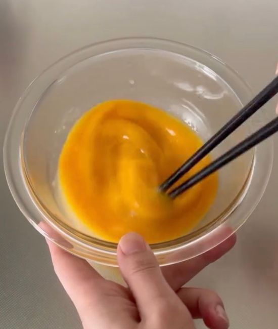 ボウルに入れた卵焼きの材料を箸で混ぜ合わせる様子