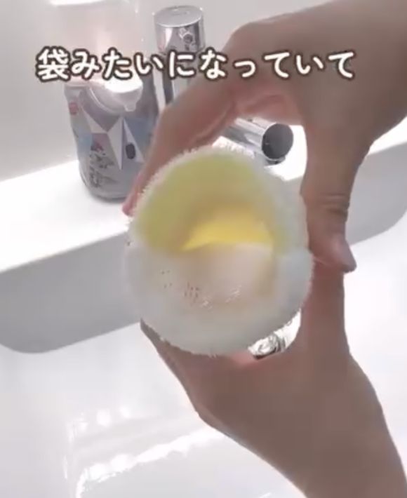 ダイソーの『石けん用スポンジ』を両手で持って袋の部分を開いた様子