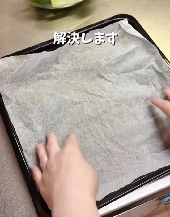 オーブンの鉄板にクッキングシートを敷く様子