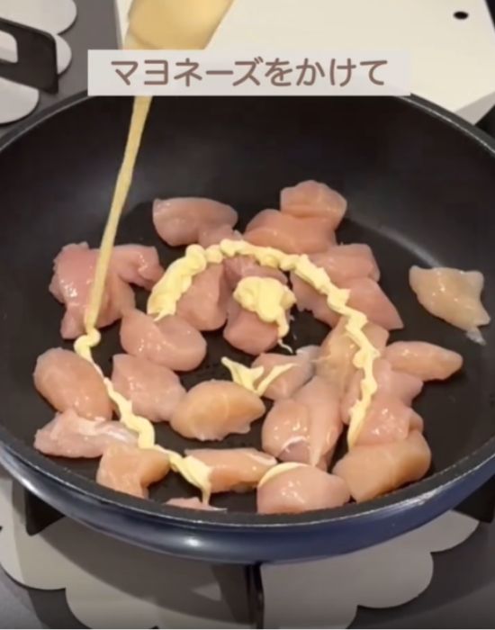 フライパンに並べた肉にマヨネーズをかける様子