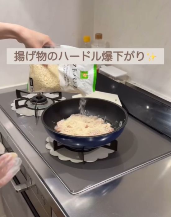 フライパンに並べた肉の上にパン粉をかける様子