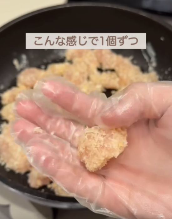 パン粉をまぶした肉を手にしている様子