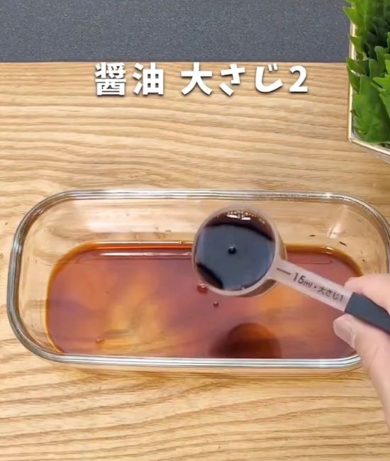 みりんの入った耐熱容器に計量スプーンで醤油を入れる様子