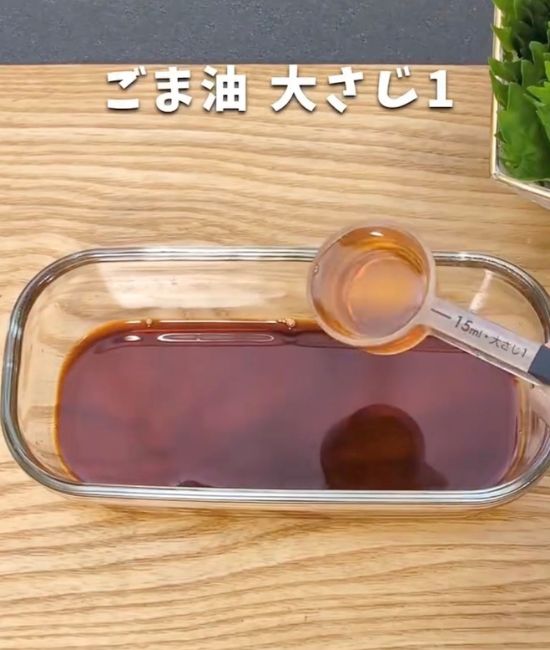 調味料の入った耐熱容器に計量スプーンでごま油を入れる様子