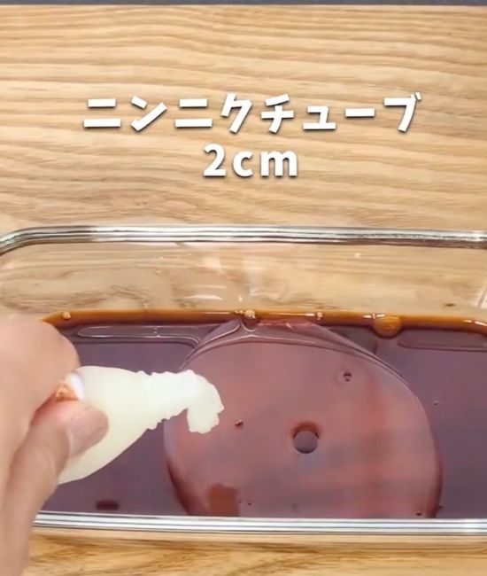 調味料を入れた耐熱容器にニンニクチューブを絞って入れる様子