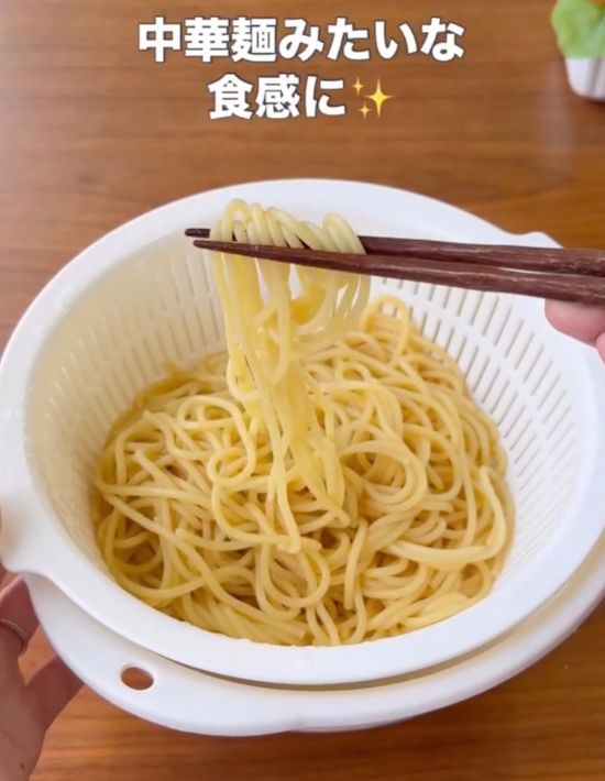 ザルにあげたパスタを箸で持ち上げている様子