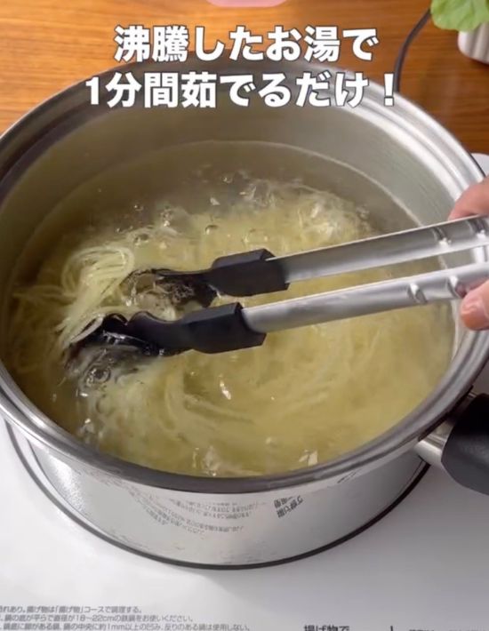 トングでかき混ぜながら鍋でパスタをゆでる様子