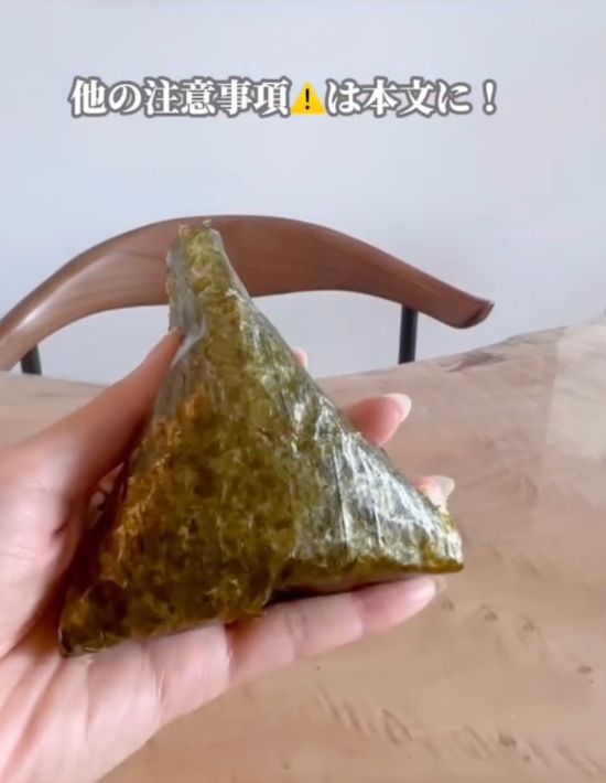 海苔が巻かれた三角おにぎりを手に持っている様子