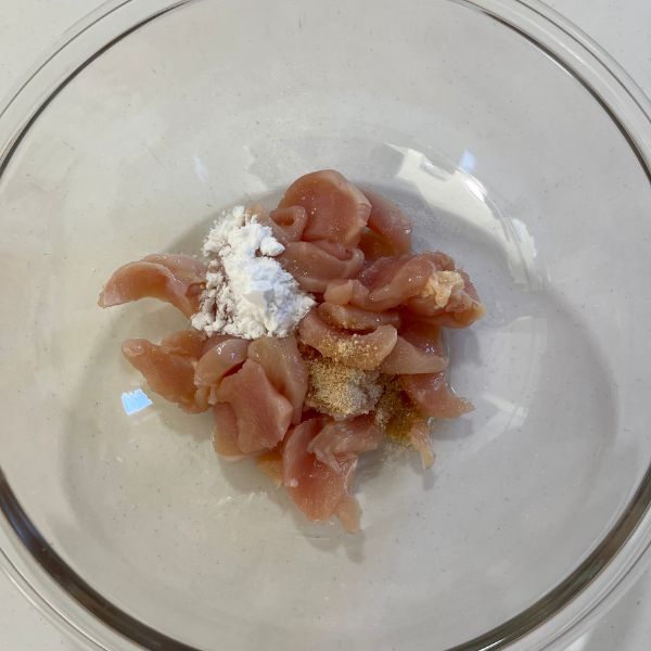 細切りにした鶏胸肉をボウルに入れて片栗粉をかけた様子
