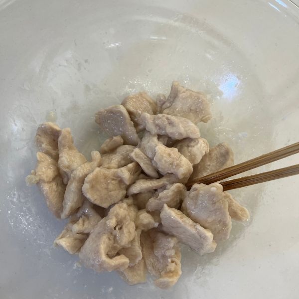 電子レンジでしっかりと加熱された鶏胸肉を箸でほぐす様子