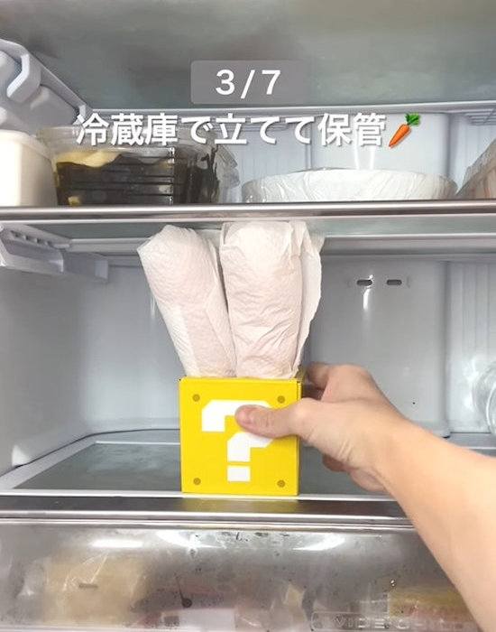 キッチンペーパーで巻いたニンジンを冷蔵庫に入れる様子