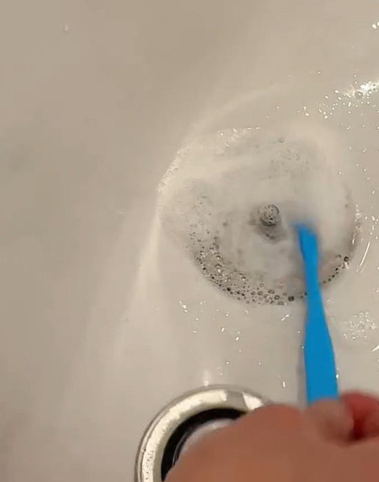 排水栓を歯ブラシで洗う様子
