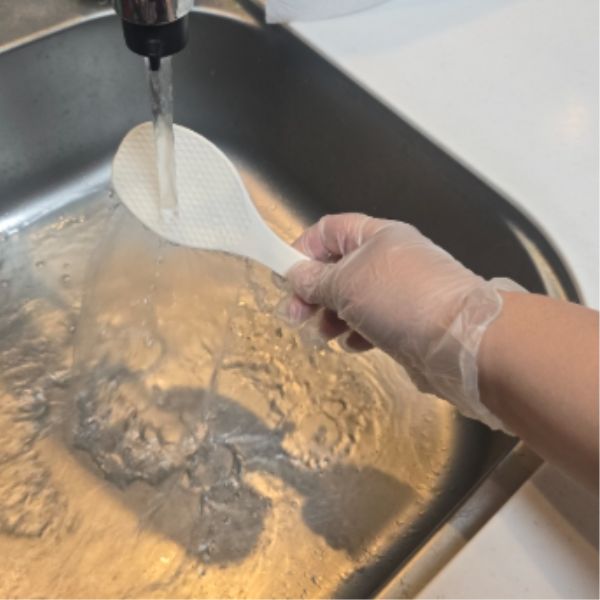 しゃもじを流水で洗う様子