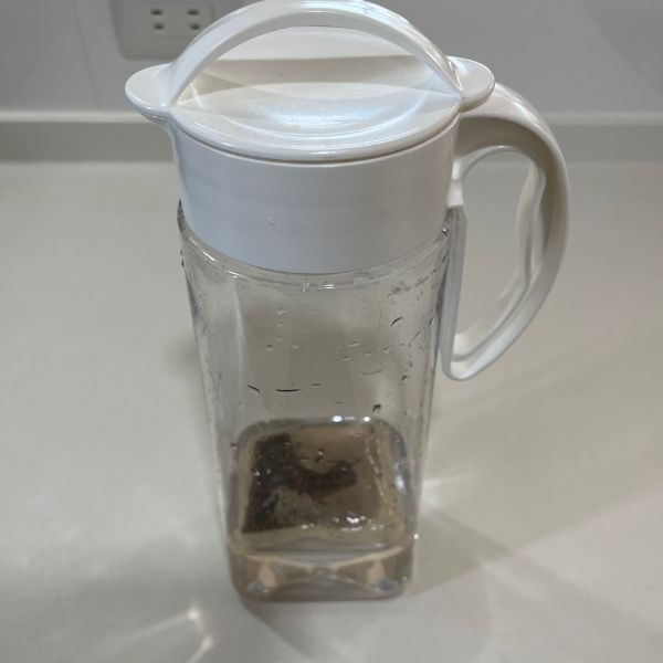少し水が入った透明なピッチャーに麦茶パックを入れて蓋をしている様子