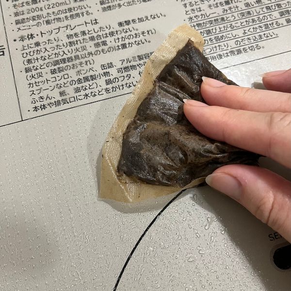 使い終わった麦茶パックでIHコンロのトッププレートをこする様子