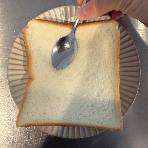 食パンにスプーンの背を押し当ててハート型を作る様子