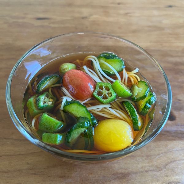 ミニトマトとオクラを入れたそうめんつゆに輪切りにしたキュウリを入れた様子