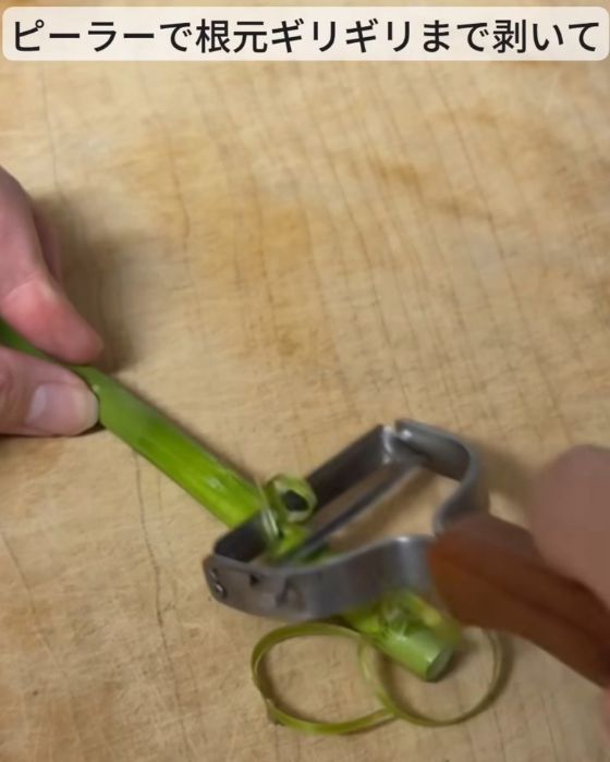 アスパラガスの根元の部分の皮をピーラーでむく様子
