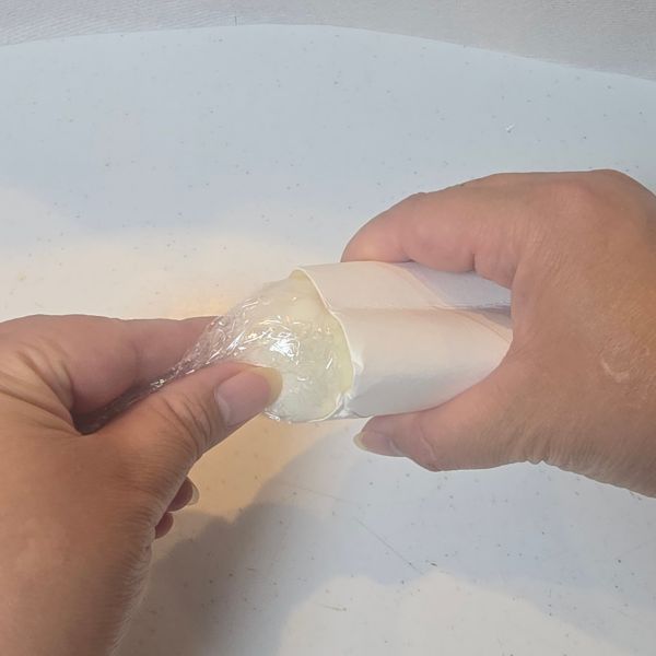 ラップで包んだゆで卵をハート型にしたキッチンペーパーの芯に入れる様子