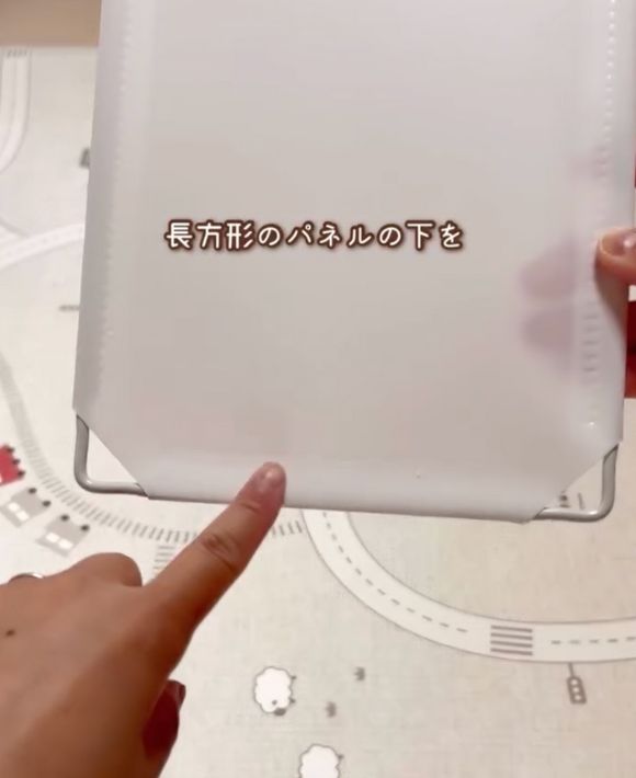 長方形のパネルの下の部分を指さしている様子