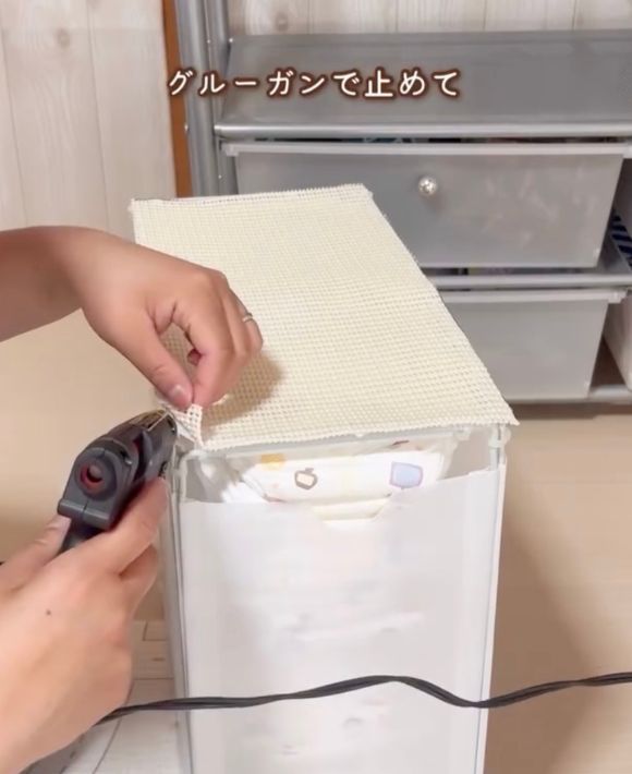 『オムツストッカー』の底の大きさに合わせて切った滑り止めシートをグルーガンでとめる様子