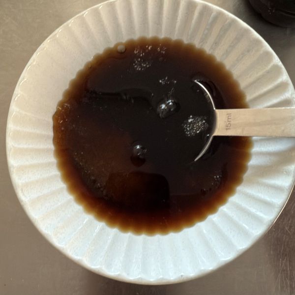 コーヒーに粉ゼラチンを加えて計量スプーンで混ぜる様子