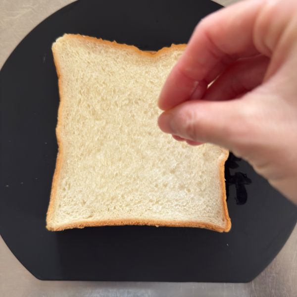 手に付けた水を払うようにして食パンをぬらす様子