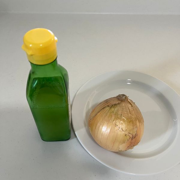 レモン果汁の瓶と皿にのせたタマネギを並べた写真
