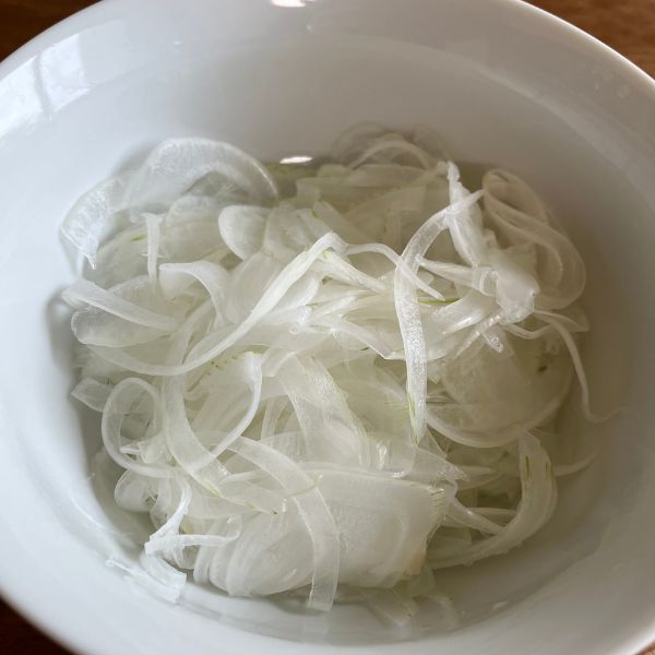 レモン水にさらした薄切りタマネギの水気を切って皿に盛った様子