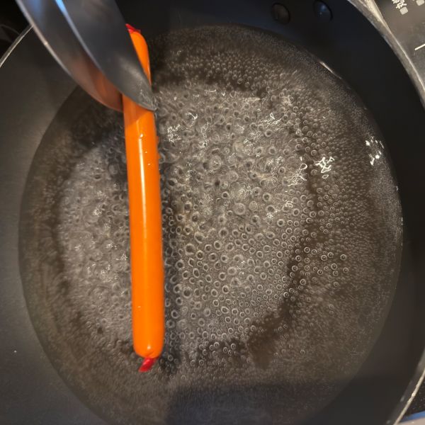 鍋に入れた魚肉ソーセージをトングで掴む様子