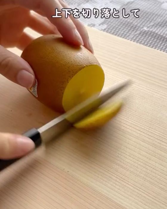 キウイの上下を包丁で切り落とす様子